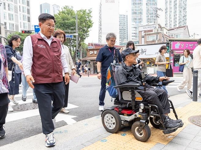 박강수 마포구청장이 휠체어를 탄 주민과 함께 새로 조성된 무장애길을 걷고 있다.(2).jpg
